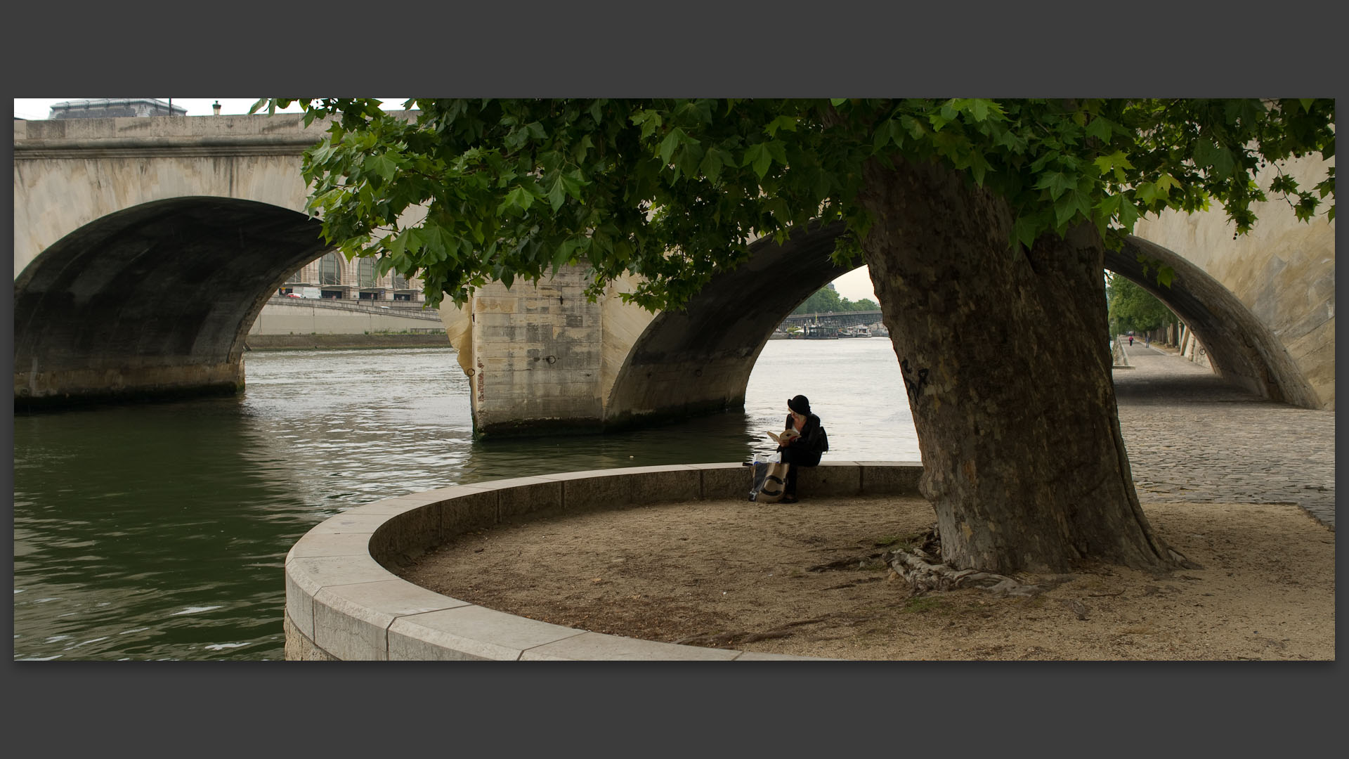 Femme lisant, port du Louvre, devant le pont Royal, à Paris.