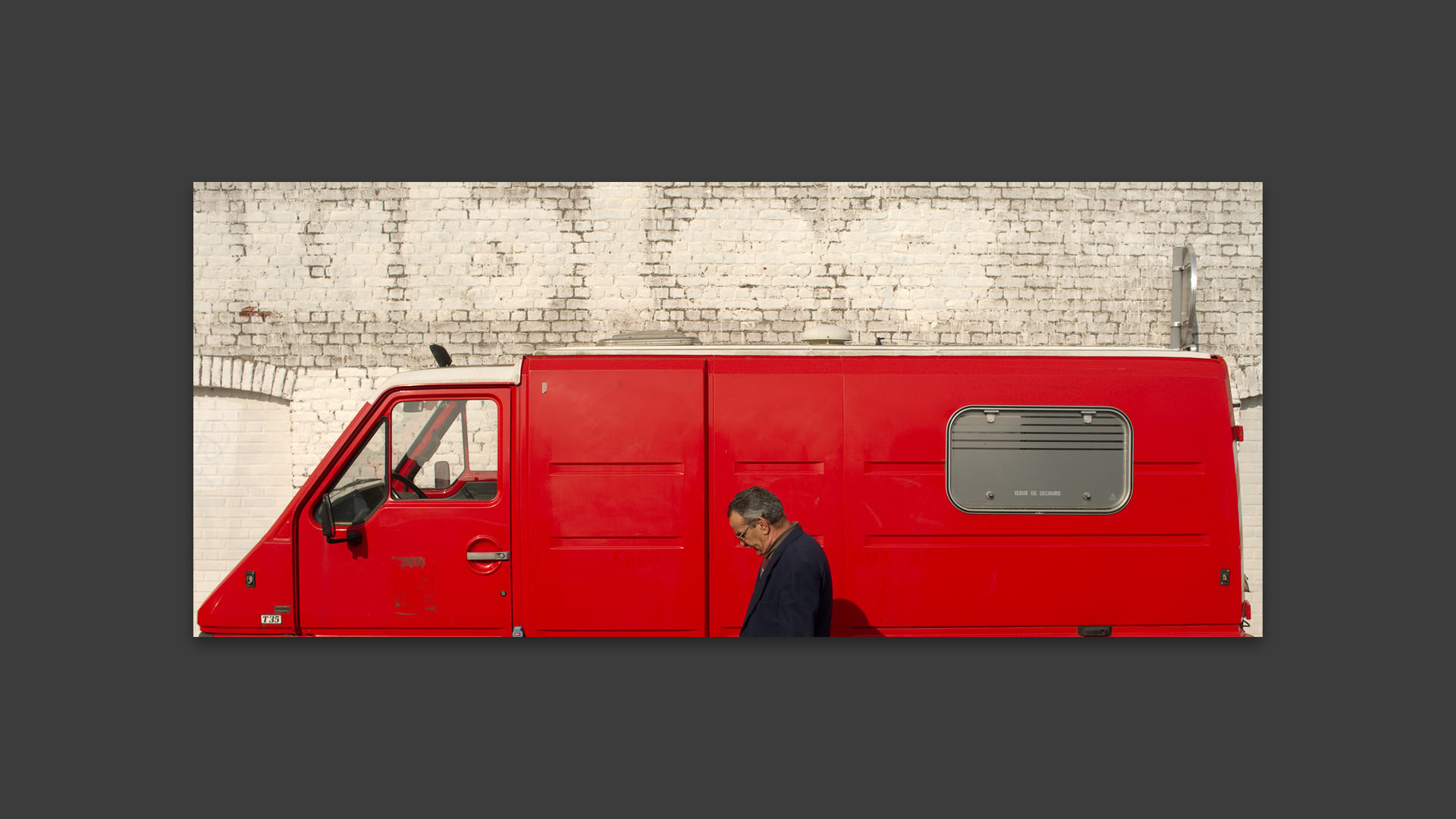 Homme passant devant une camionnette rouge, rue d'Avesnes, à Lille.