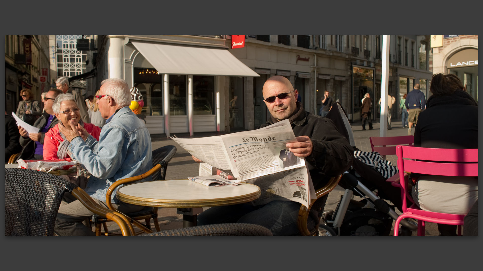 Homme lisant le Monde à la terrasse d'un café, sur le parcours de la manifestation contre la réforme des retraites.