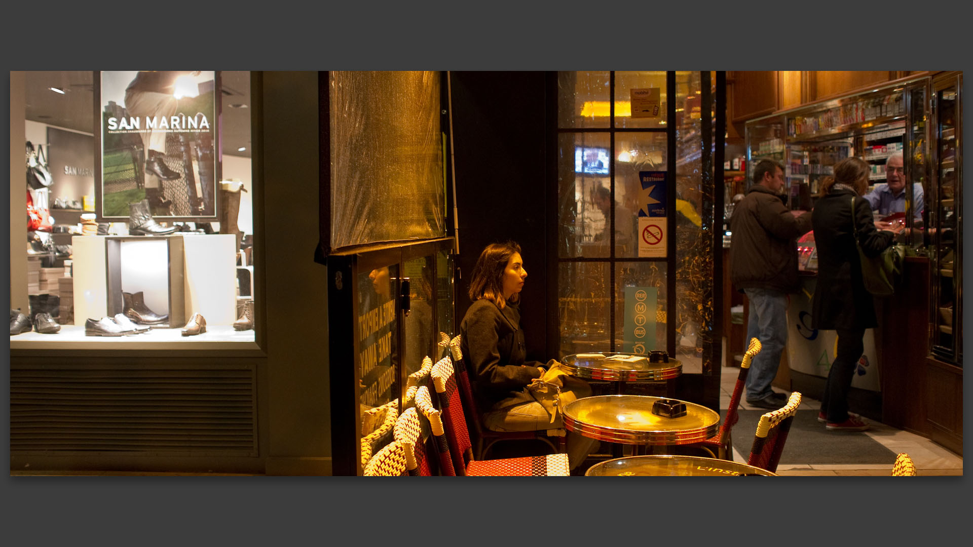 Jeune femme songeuse à la terrasse d'un café, place Saint-Michel, à Paris.