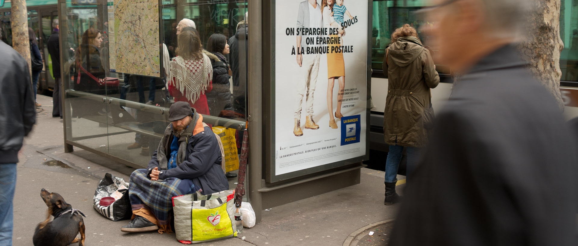 Mendiant assis contre un abribus, boulevard Saint-Germain, à Paris.