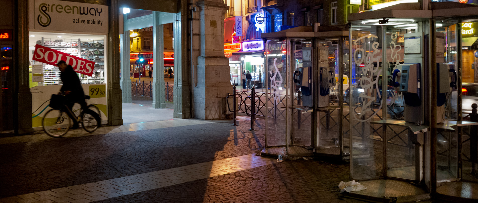 Cycliste et cabines téléphoniques, place de la Gare, à Lille.