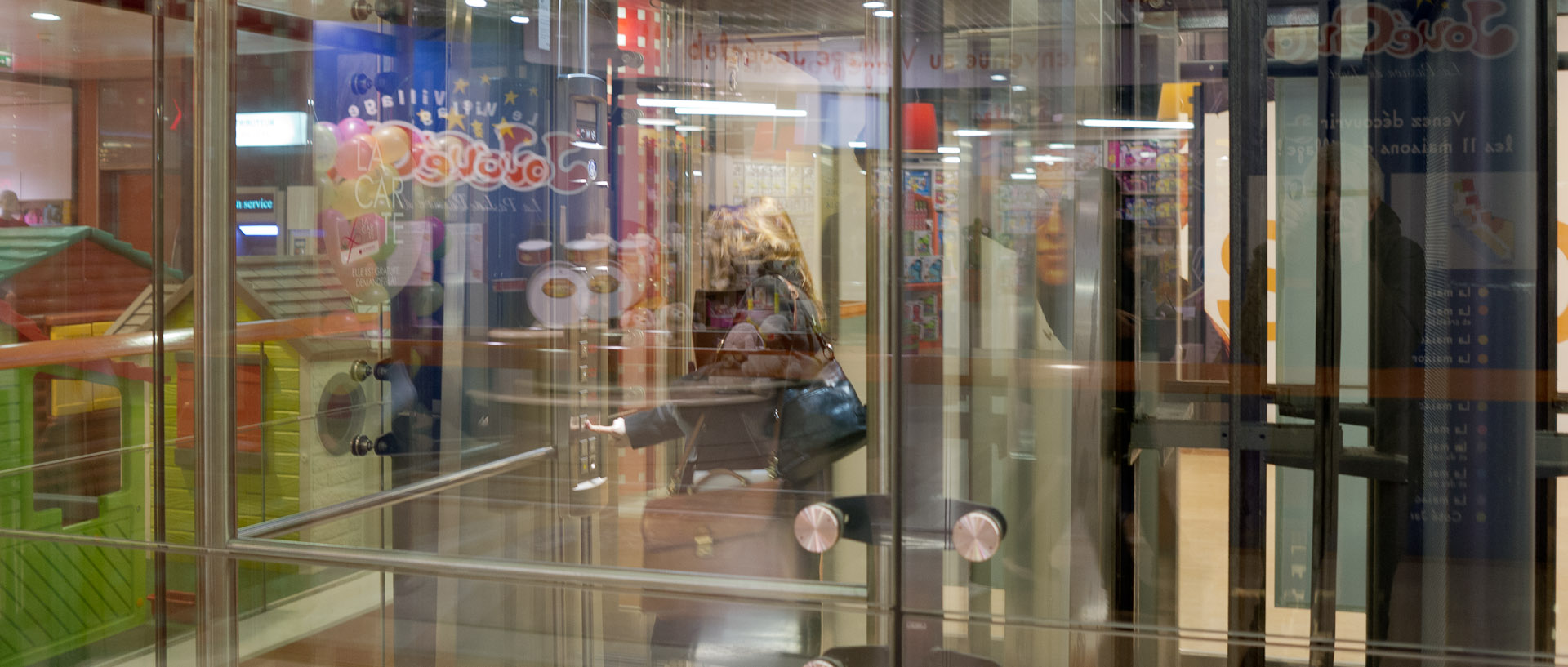 Femme dans un ascenseur vitré, centre commercial des Tanneurs, à Lille.