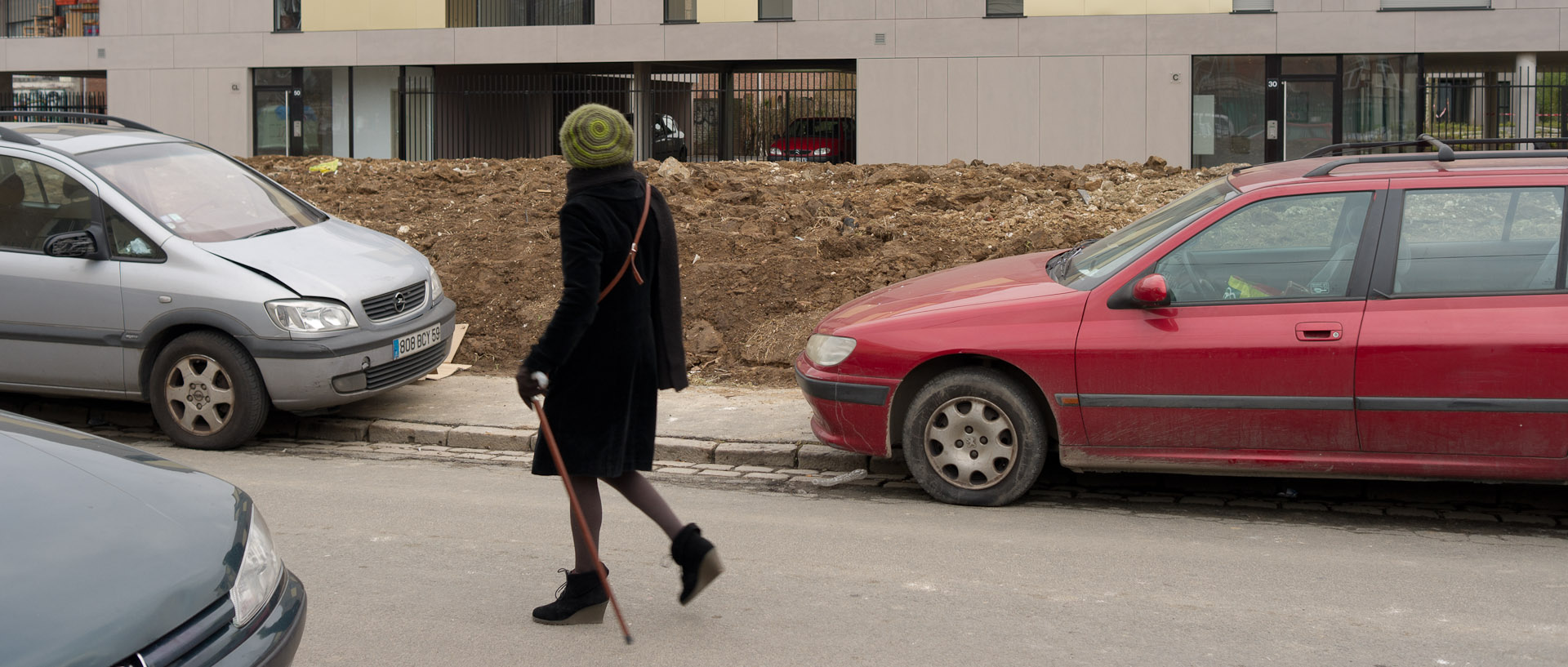 Femme avec une canne passant devant de nouveaux immeubles, rue de Wagram, à Wazemmes, Lille.