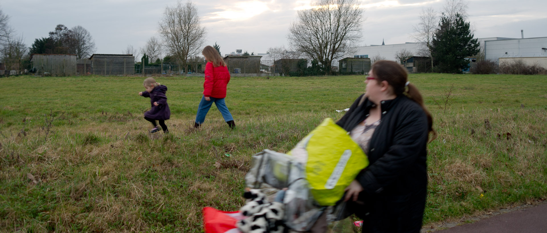 Femme avec deux enfants et une poussette chargée de sacs, rue Robert-Schumann, à Tourcoing.