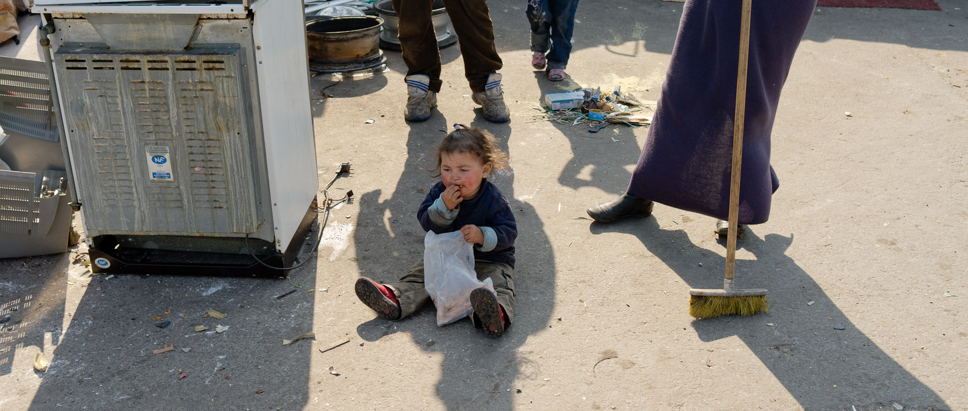 Enfant mangeant par terre, dans un campement Roms, porte d'Arras, à Lille.