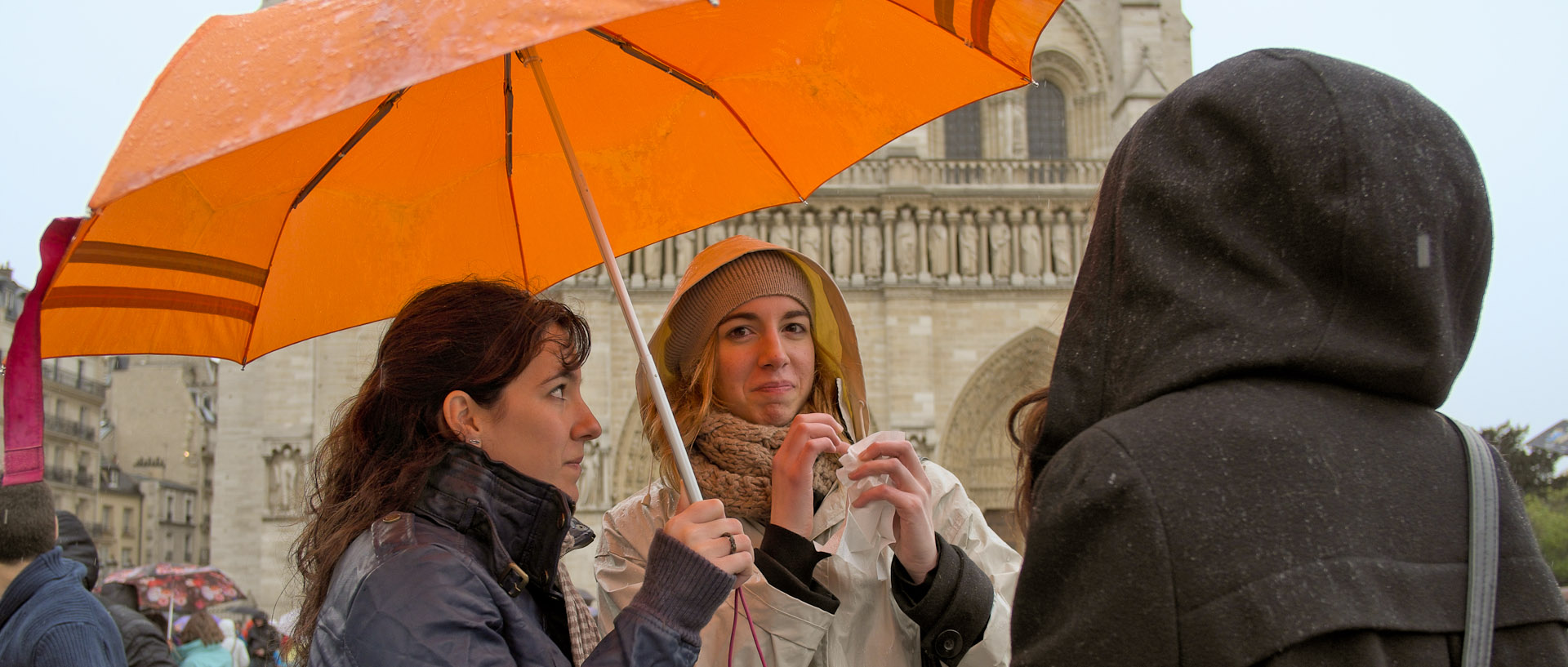 Touristes sous un parapluie, devant Notre Dame de Paris.