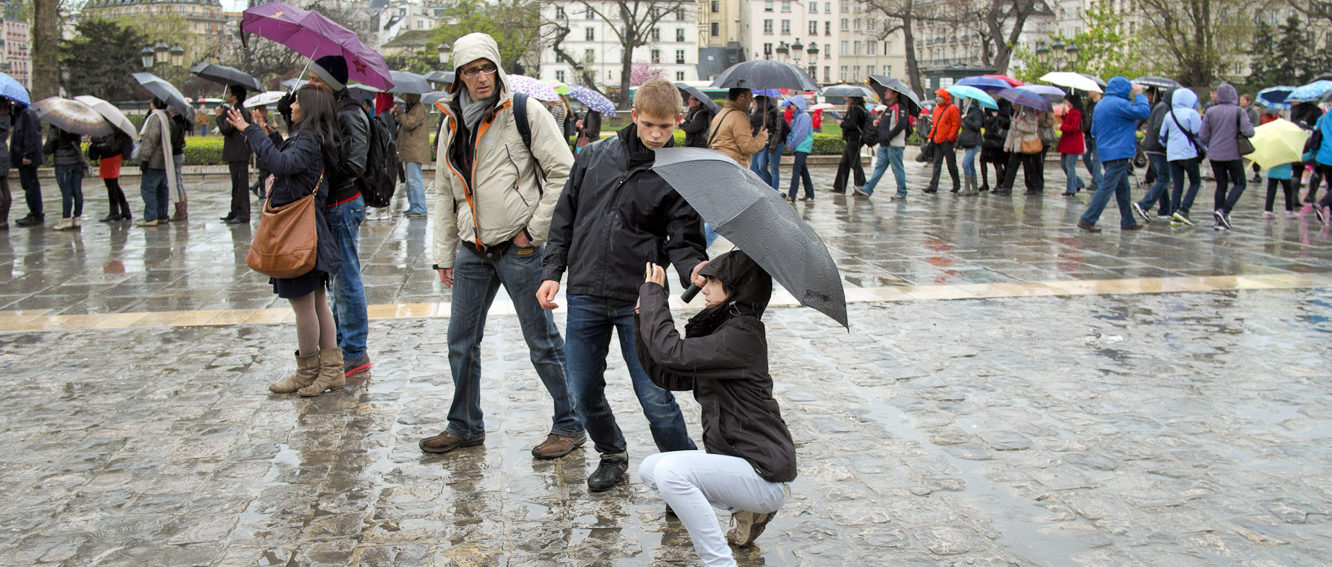 Touristes photographiant sous un parapluie, devant Notre Dame de Paris