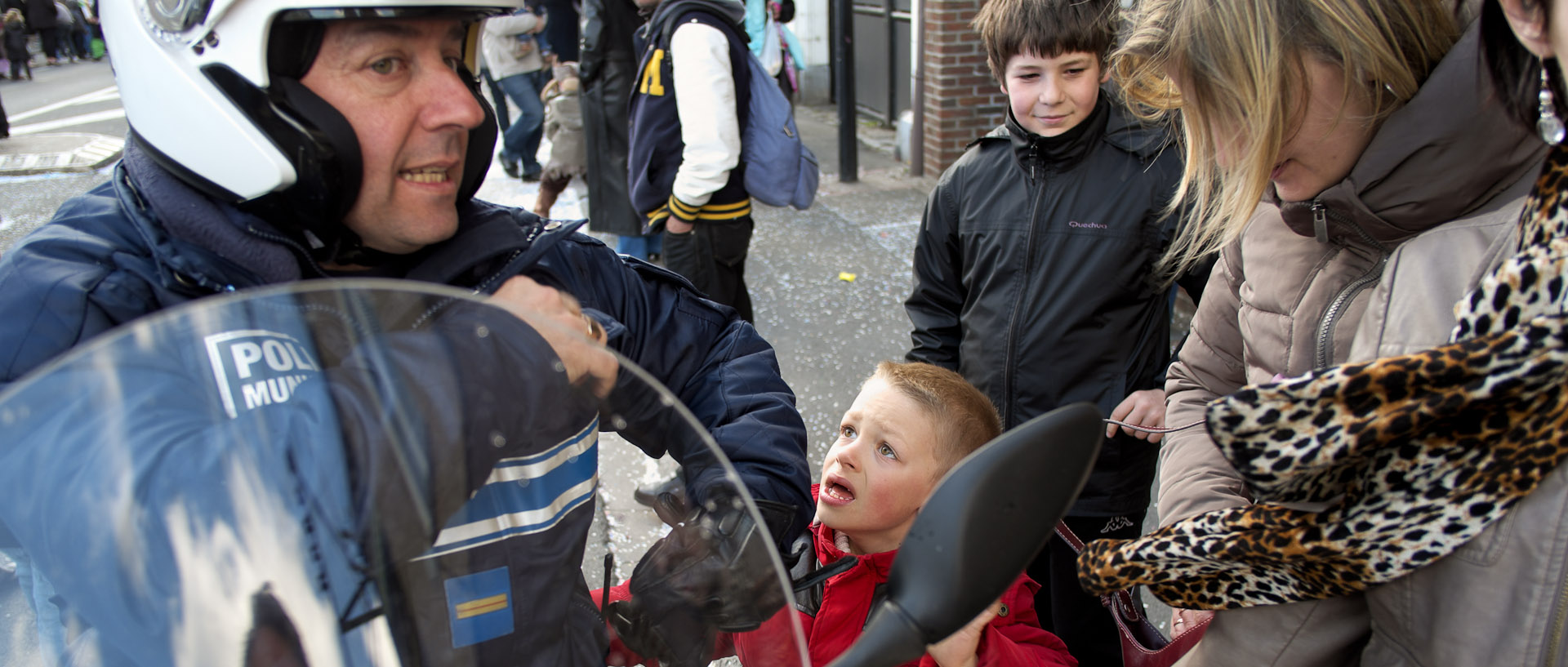 Enfant regardant avec des yeux suppliants un policier municipal sur sa motocyclette, rue Carnot, à Wattrelos.