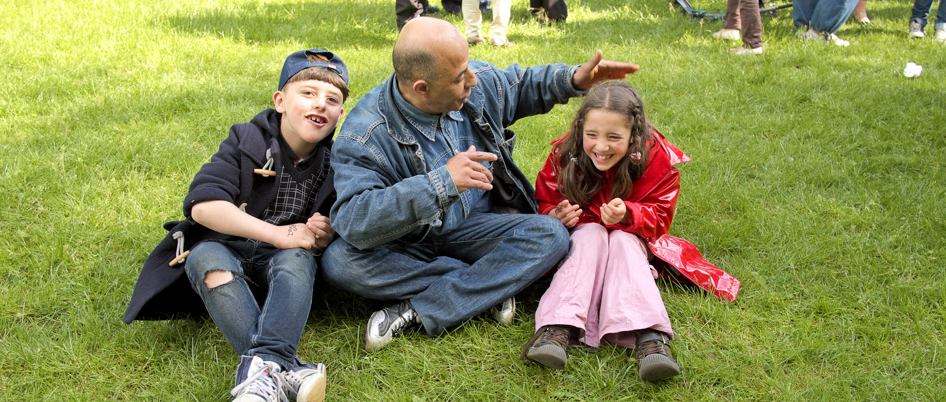 Un père et ses enfants assis sur l'herbe, pendant la fête de quartier des Hauts Champs, à Roubaix.