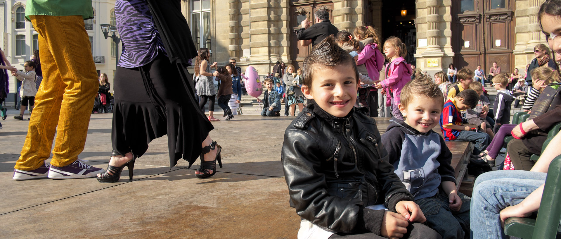 Enfants assis sur une estrade devant des danseurs de tango, pendant le festival des Arts de la rue, à Tourcoing.