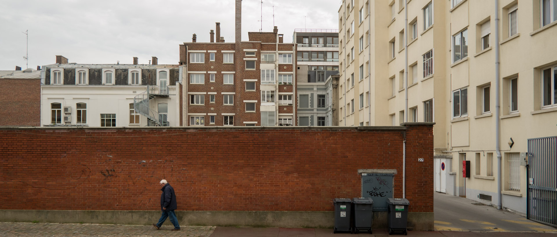 Homme marchant le long d'un mur, rue de la Baignerie, à Lille.