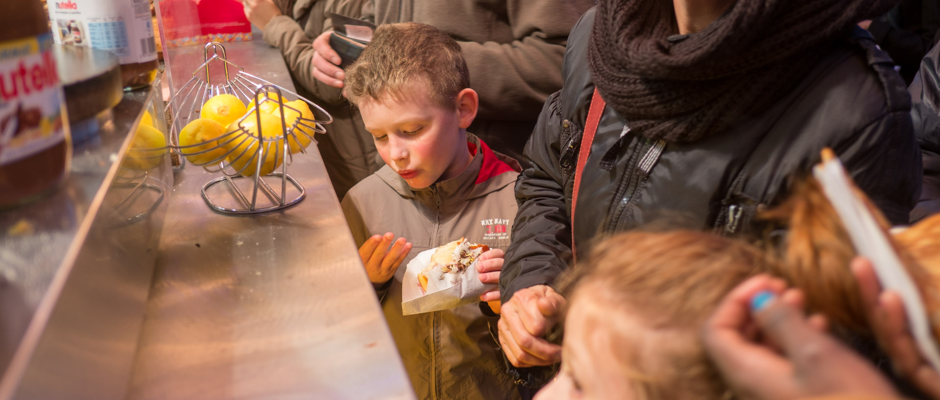 Enfant mangeant une gaufre dans le marché de Noël de Lille.