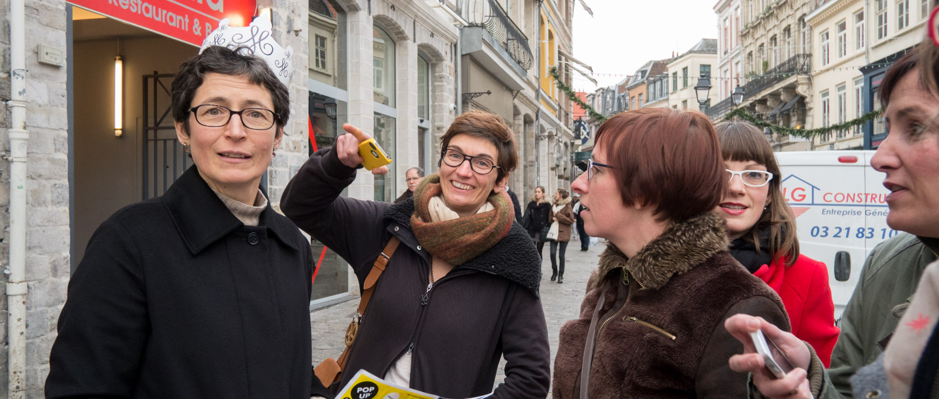 Femme avec une couronne en papier faisant du tourisme avec des amies, rue Esquermoise, à Lille.
