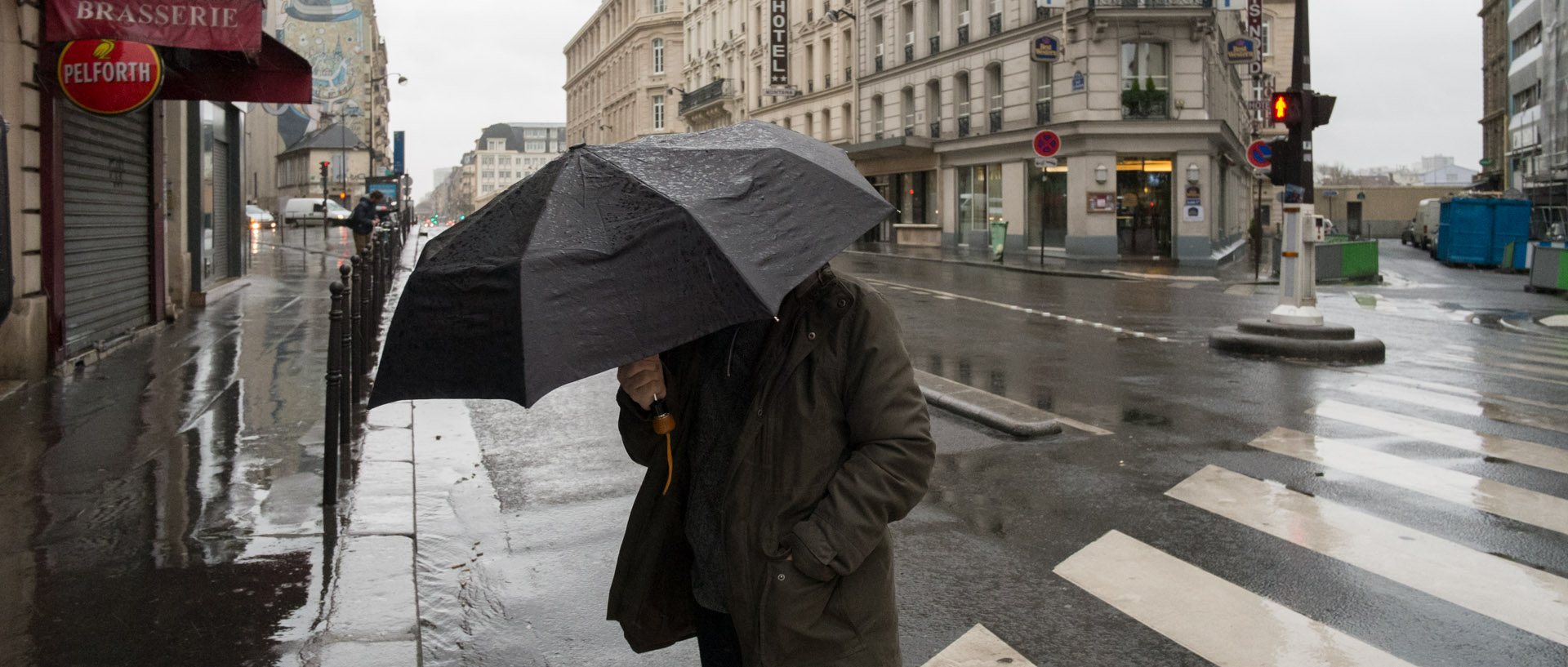 Homme avec un parapluie sous la pluie, rue La Fayette, à Paris.