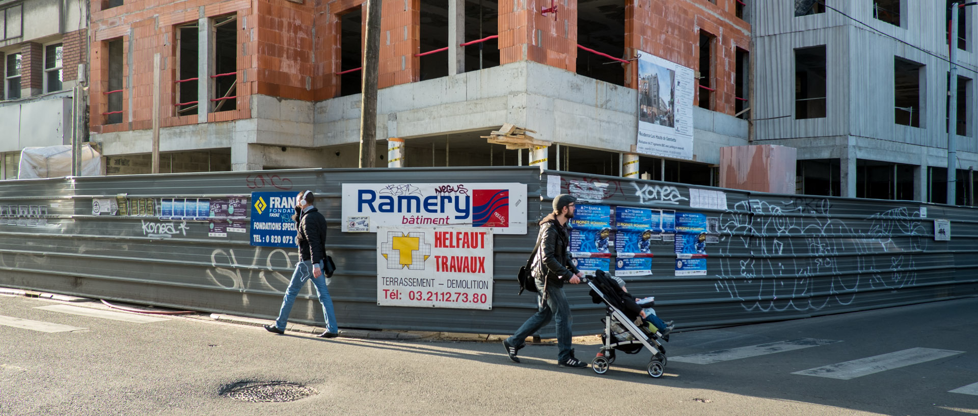 Passants devant un immeuble en construction, rue Gambetta, à Wazemmes, Lille.