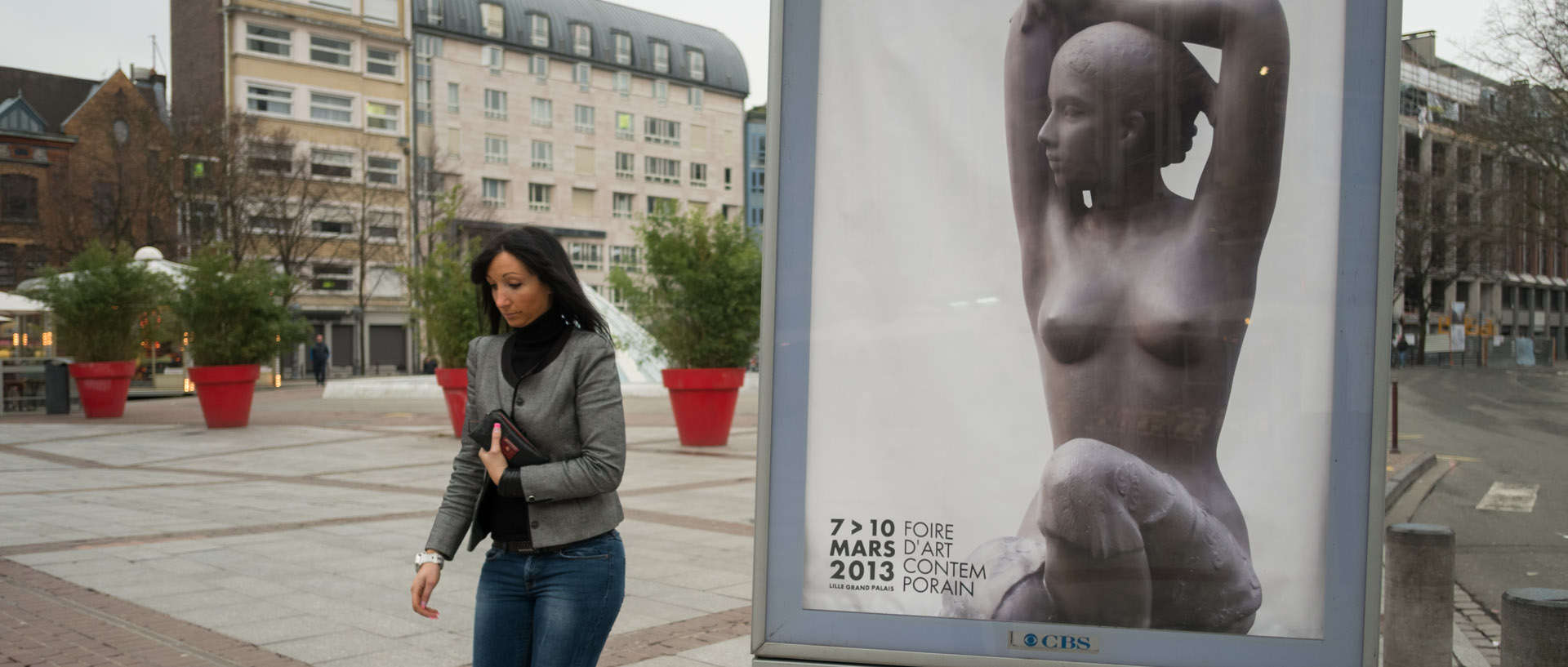 Femme passant à côté d'un panneau publicitaire, place Rihour, à Lille.