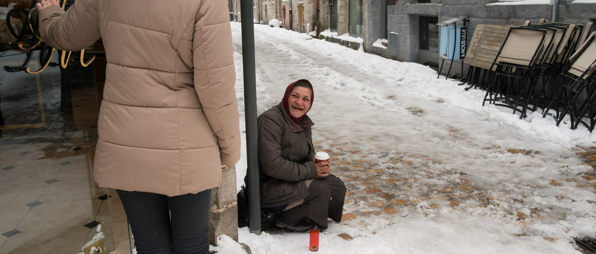 Mendiante assise dans la neige, rue de la Monnaie, à Lille.