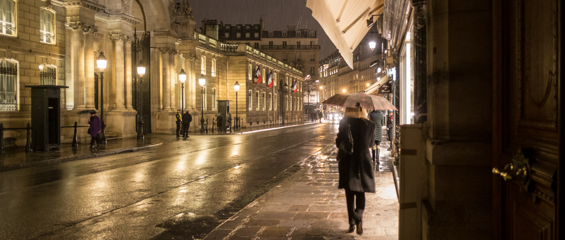 Femme marchant sous une averse, devant le palais de l'Elysée, à Paris.