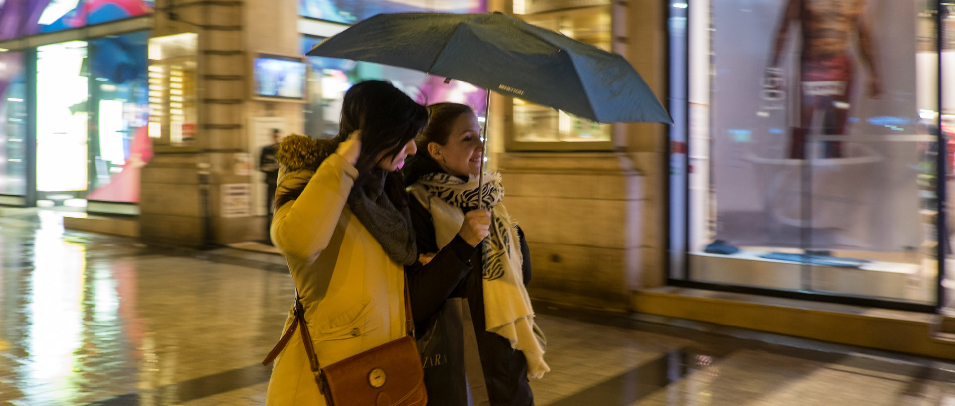 Deux femmes sous un parapluie, pendant une averse sur les Champs Elysées, à Paris.