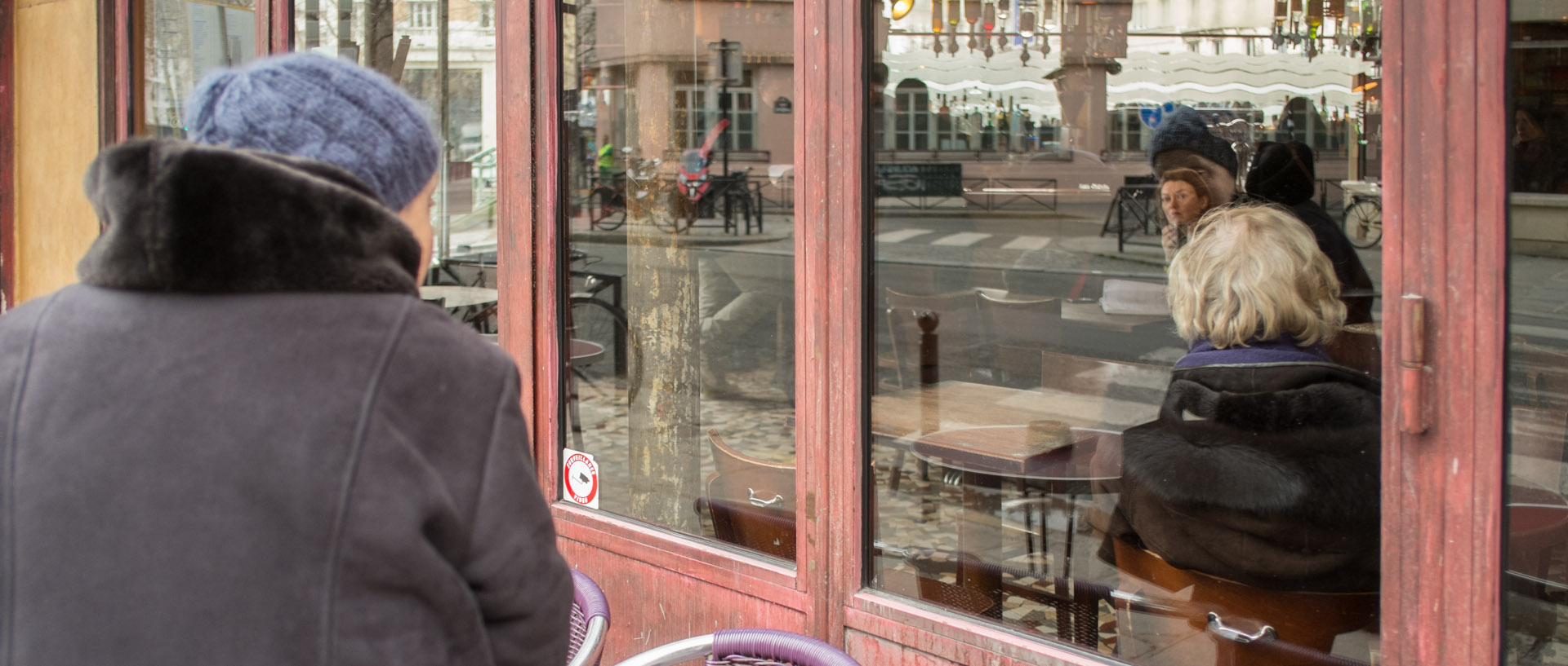 Femme regardant à travers la vitrine d'un café, rue Beaurepaire, à Paris.