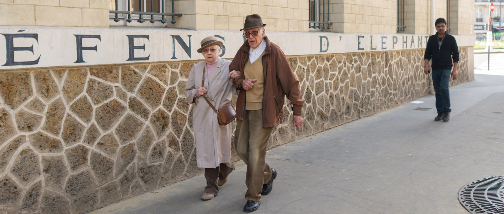 Couple âgé devant un mur indiquant "Défense d'éléphant", rue Louis-Blanc, à Paris.