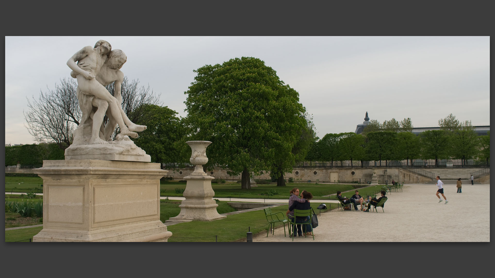 Jeune couple s'embrassant sous une statue, au jardin des Tuileries, à Paris.