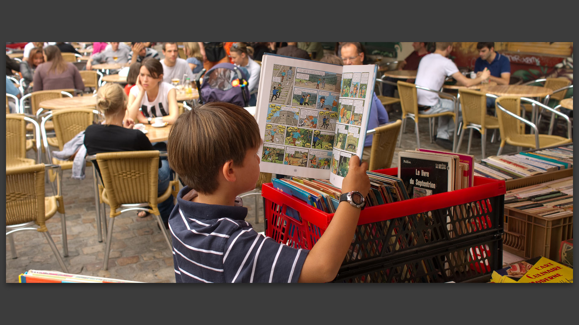 Gamin lisant Tintin et les Picaros au marché de Wazemmes, parvis de Croix, à Lille.