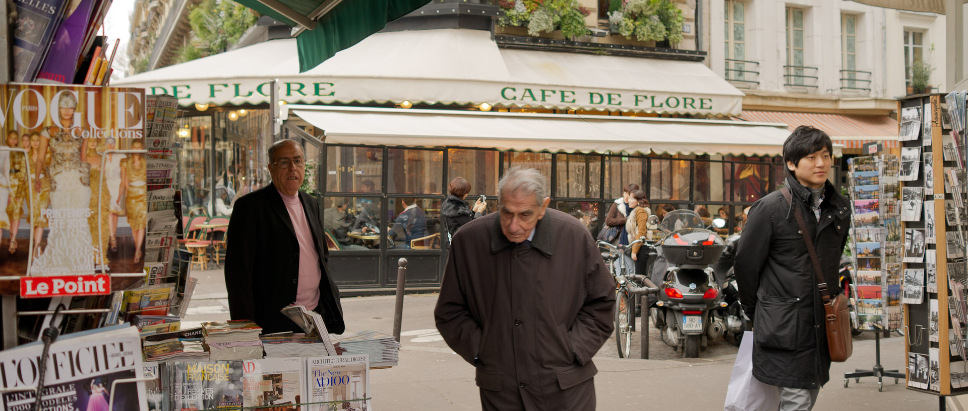 Vieil homme devant un kiosque à journaux, devant le café de Flore, boulevard Saint-Germain, à Paris.
