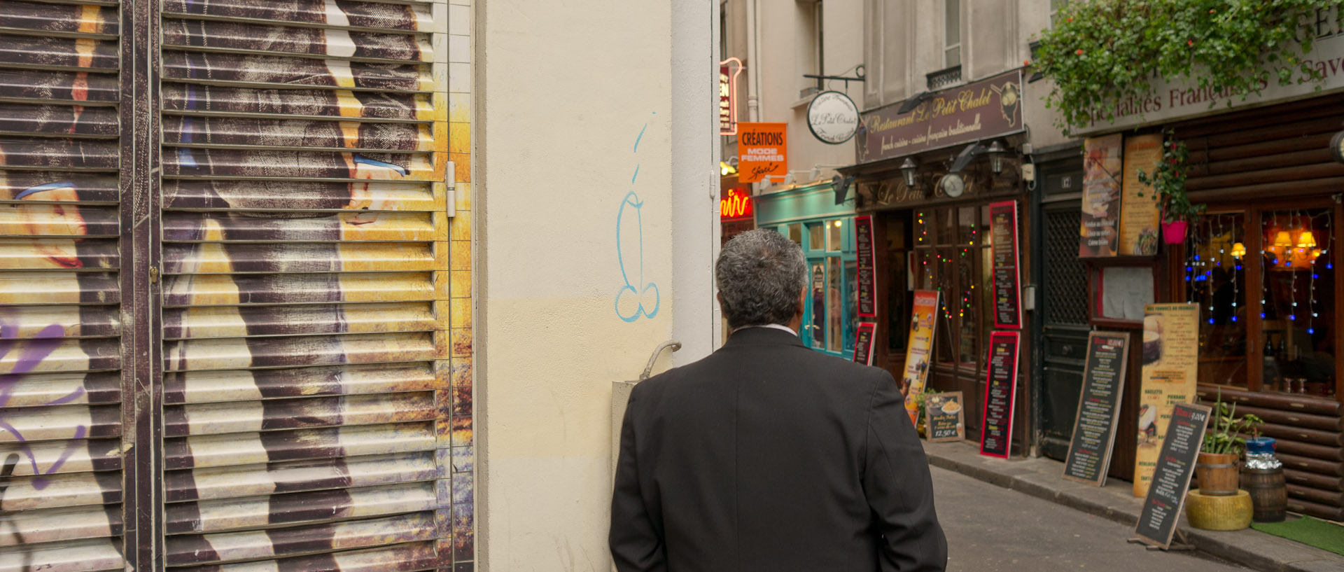 Homme passant devant un mur tagué, rue Grégoire de Tours, à Paris.