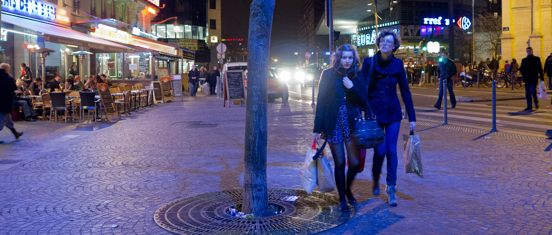 Deux femmes dans une lumière bleue, place de la Gare, à Lille.