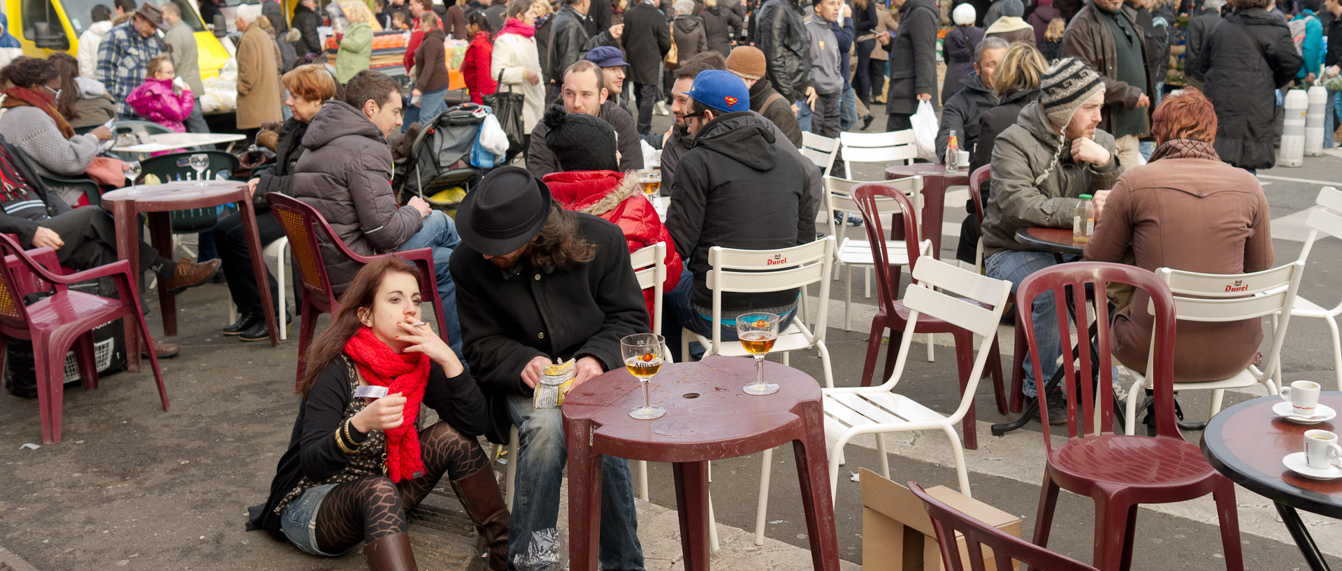 Fille assise sur le trottoir, à la terrasse d'un café, rue des Sarrazins, à Wazemmes, Lille.