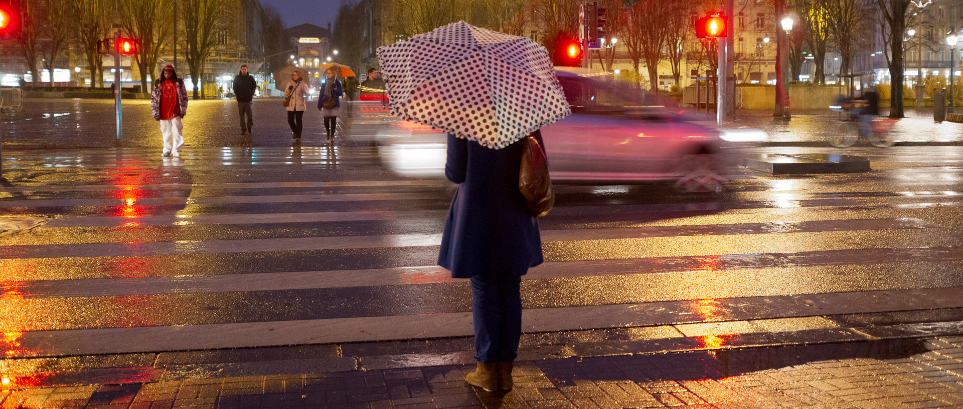 Femme avec son parapluie attendant à un feu rouge, boulevard de la Liberté, à Lille.