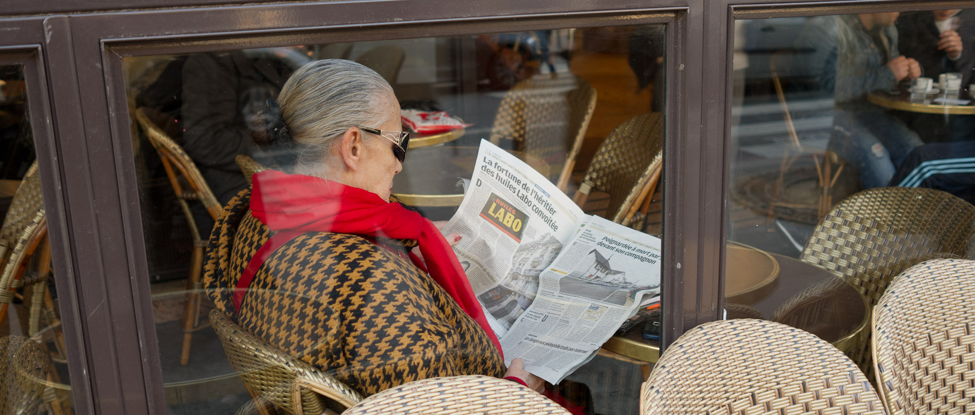 Femme lisant son journal à la terrasse d'un café, boulevard Saint-Michel, à Paris.