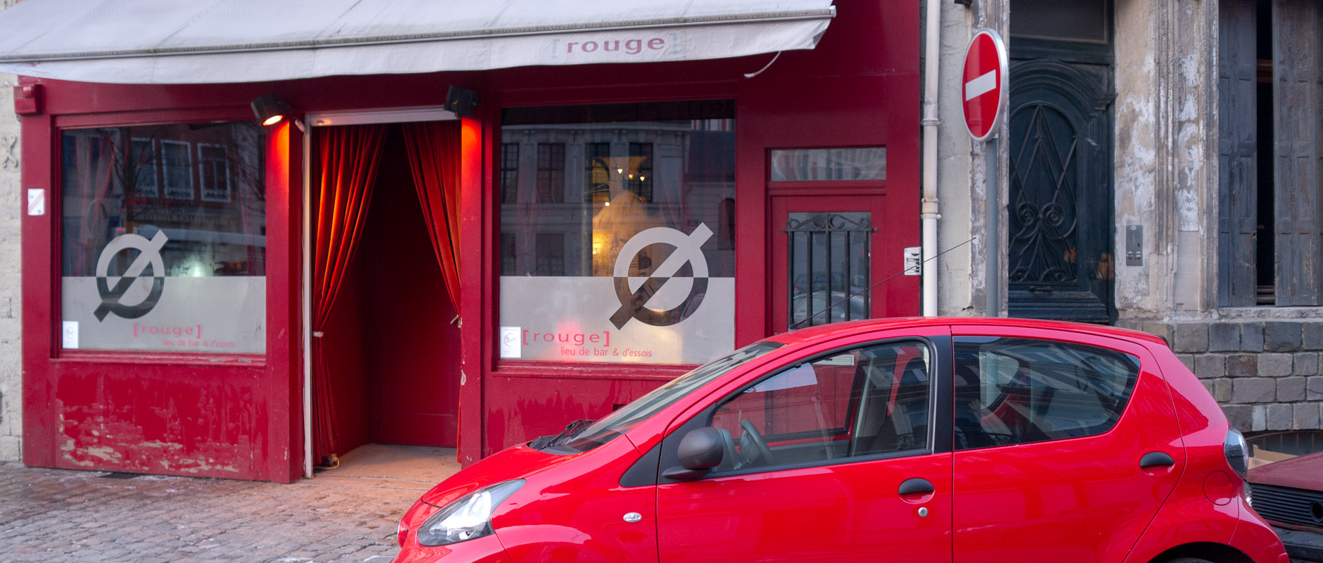 Voiture rouge devant le bar Rouge, place Saint-André, à Lille.