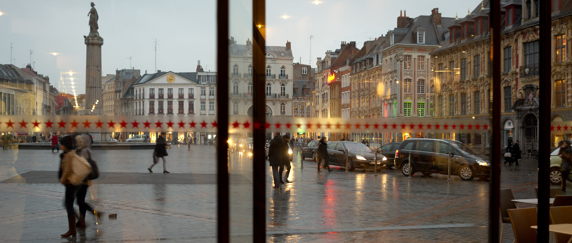 La place du Général-de-Gaulle vue à travers une porte vitrée, à Lille.