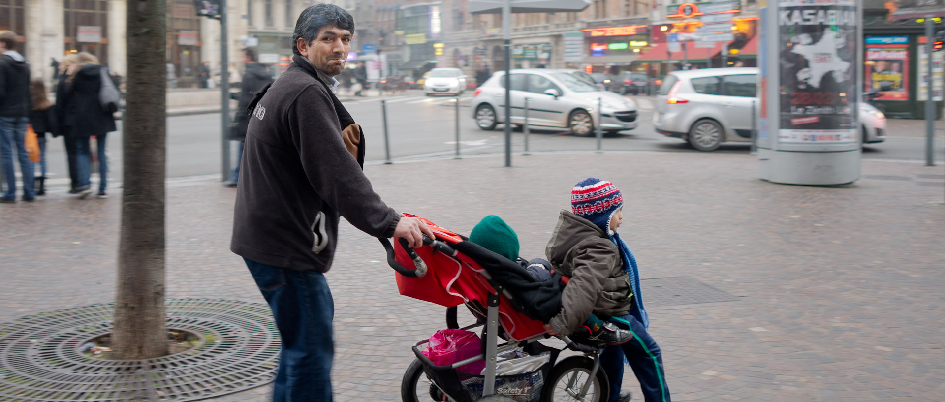 Homme avec ses enfants dans une poussette, place de la Gare, à Lille.