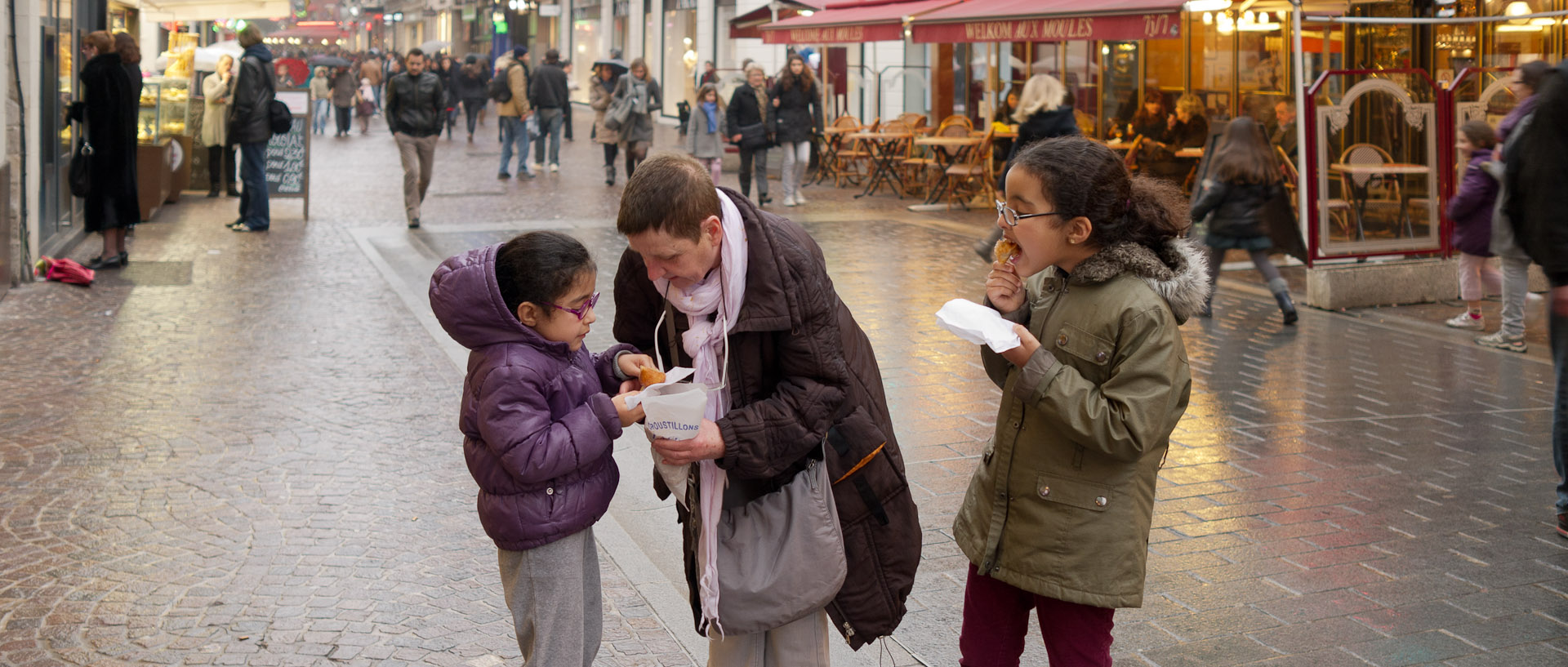 Grand mère donnant des croustillons à ses petites filles, rue de Béthune, à Lille.