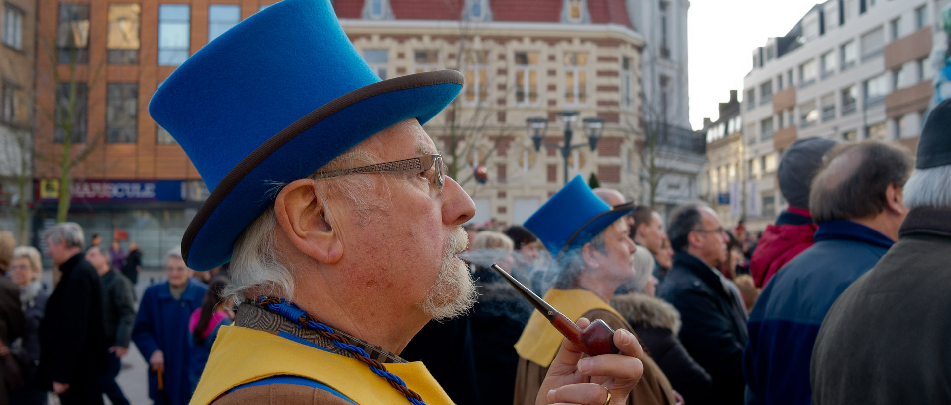 Homme avec un haut de forme bleu et une pipe, au carnaval de Tourcoing, place Victor Hassebroucq.