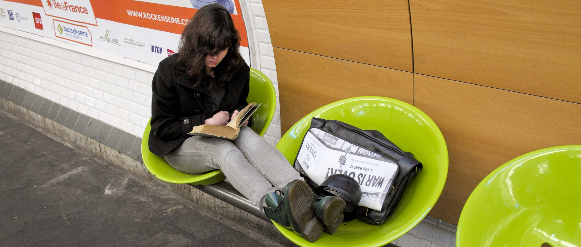 Jeune fille lisant un livre dans une station de métro, à Paris.