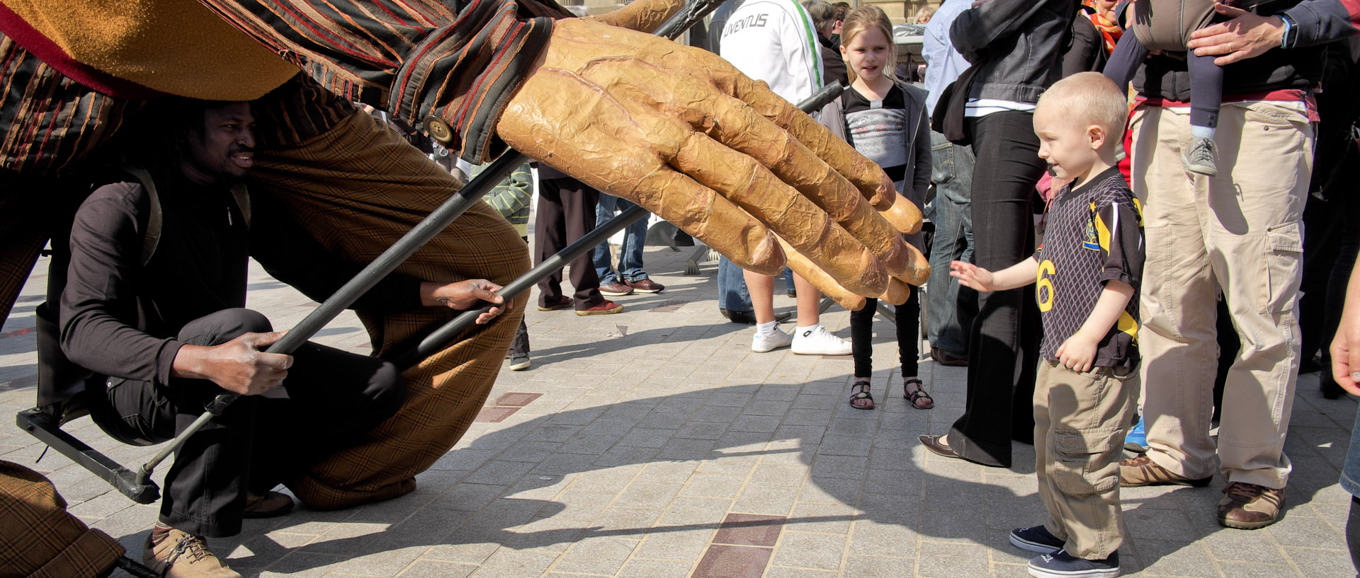 Enfant tendant sa main vers celle d'un géant, pendant le festival des Arts de la rue, à Tourcoing.