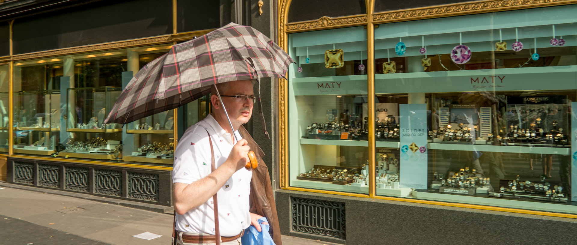 Homme avec un parapluie, sous le soleil, boulevard des Capucines, à Paris.