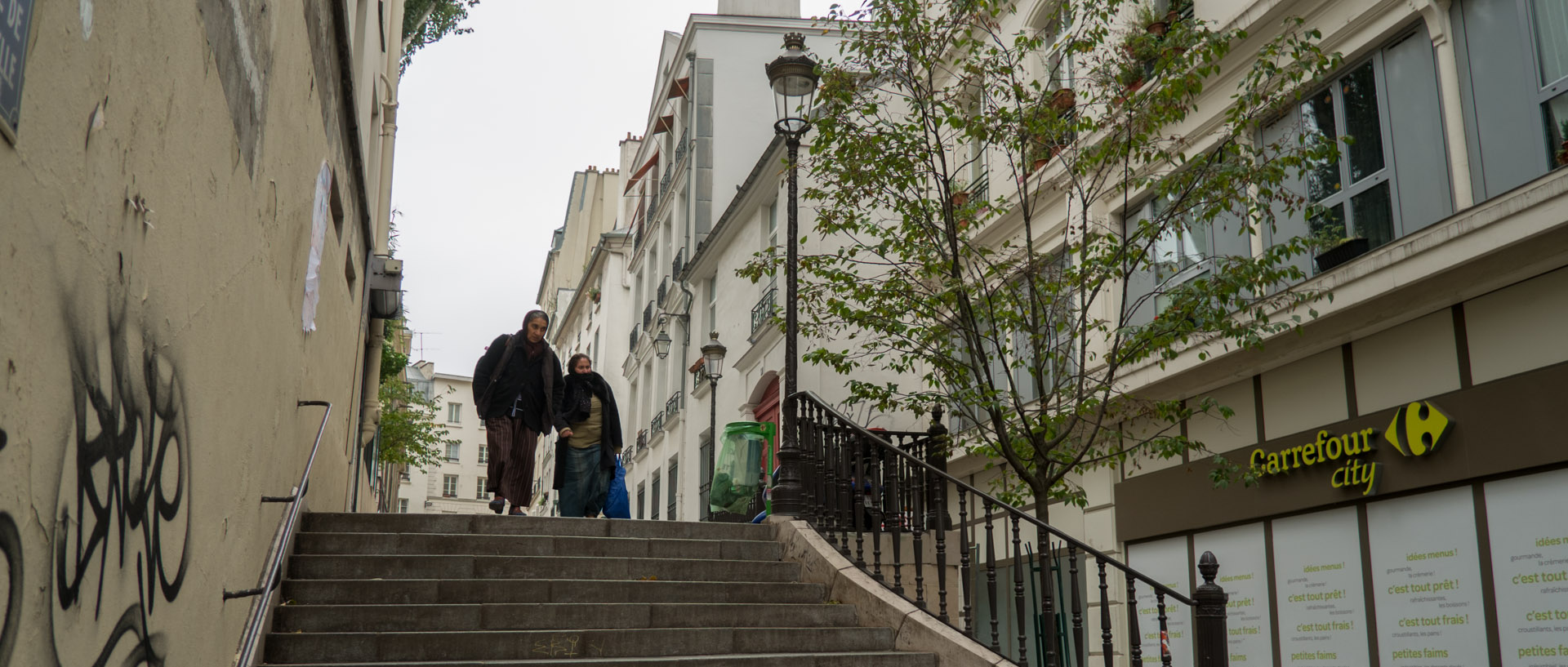 Deux femmes passant le long d'un Carrefour city, rue Notre-Dame de Bonne Nouvelle, à Paris.