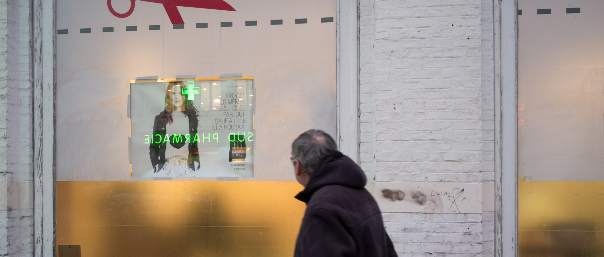 Homme passant devant une vitrine, rue de faubourg des Postes, à Lille.