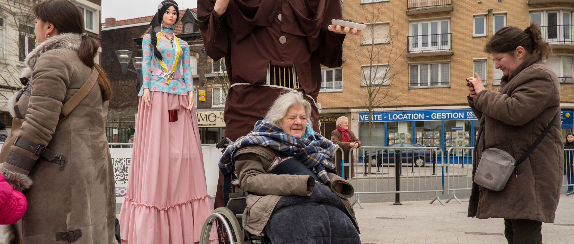 Femme en fauteuil roulant se faisant photographier devant des géants, pendant le week-end Geant, à Tourcoing.