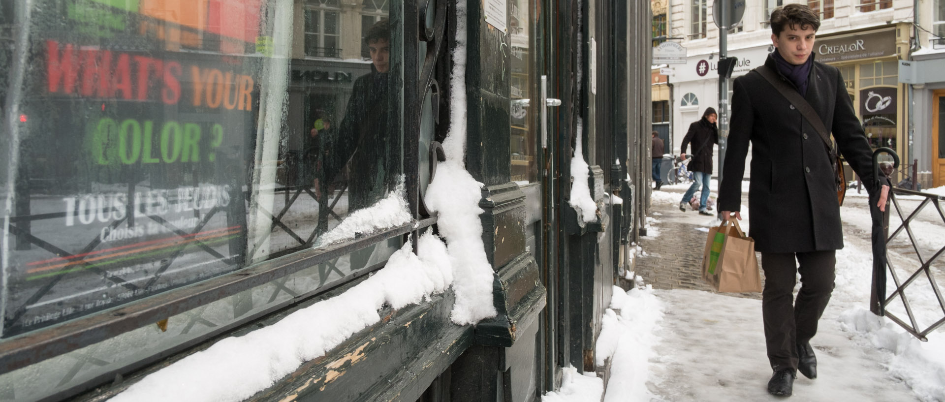 Jeune homme marchant dans la neige, rue Royale, à Lille.