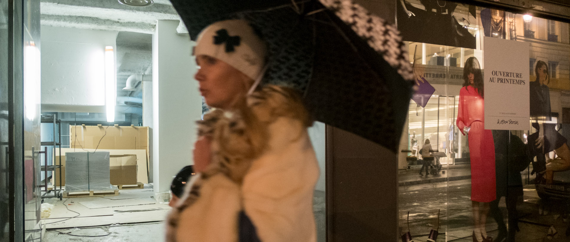Femme avec un parapluie devant une boutique en rénovation, rue Saint-Honoré, à Paris.