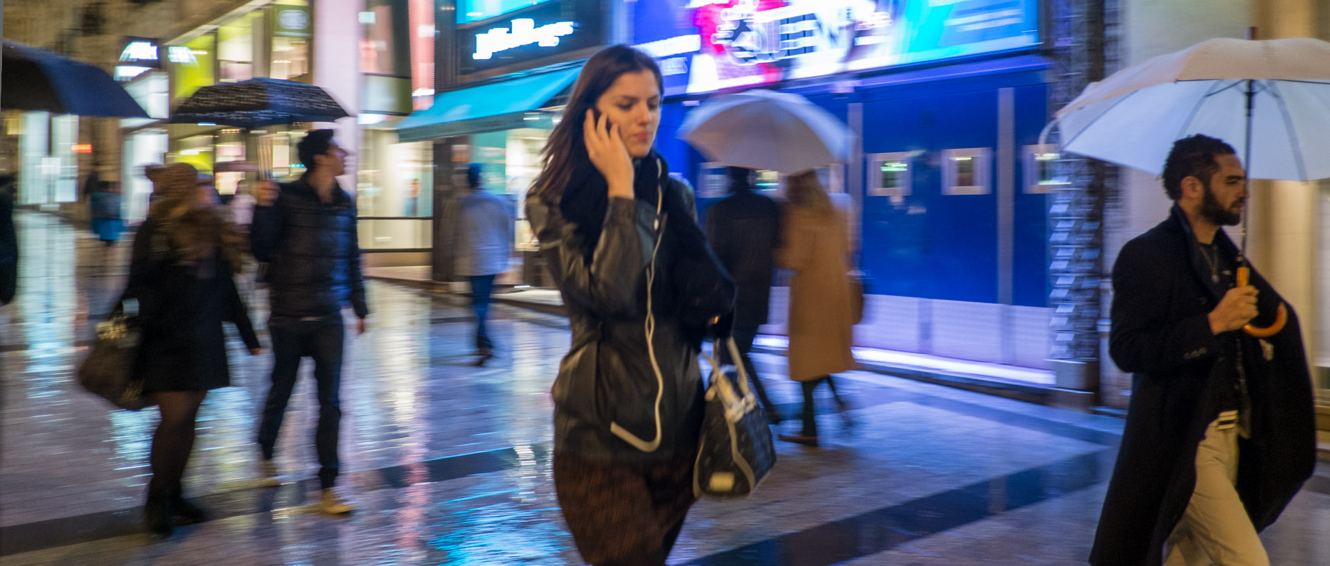 Femme avec son téléphone portable, sous la pluie, avenue des Champs Elysées, à Paris.