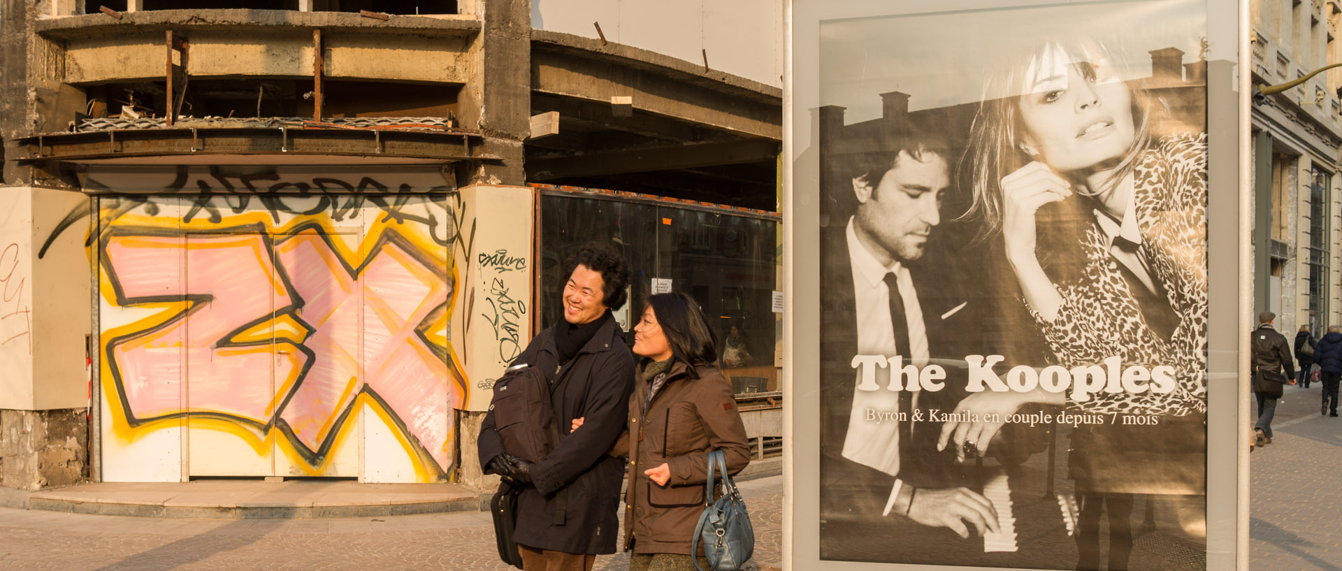 Couple asiatique passant à côté d'une affiche publicitaire, rue Faidherbe, à Lille.