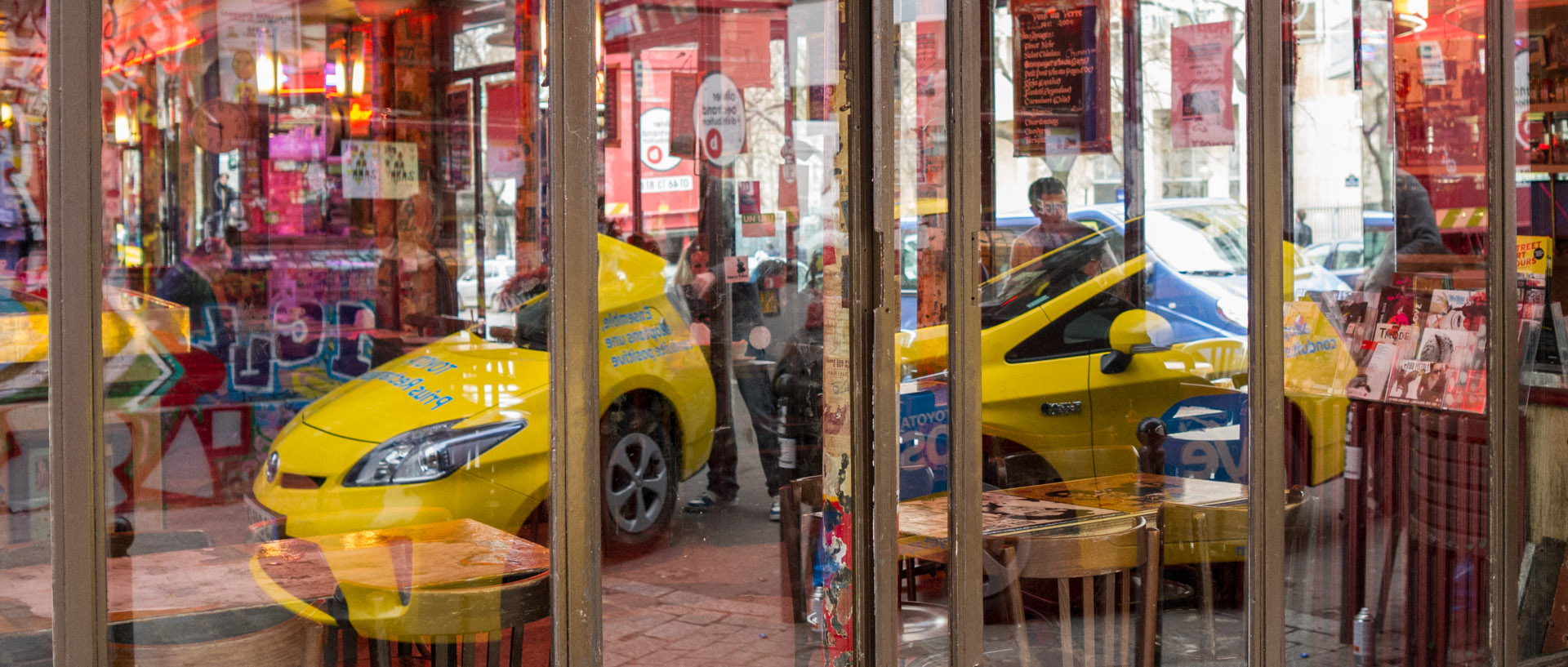 Reflet d'une voiture dans une vitrine de café, rue Denoyez, à Paris.